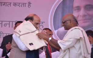 Madhu Pandit Dasa, Chairman felicitating Sri Rajnath Singh, Minister of Home Affairs, with a shawl on stage.